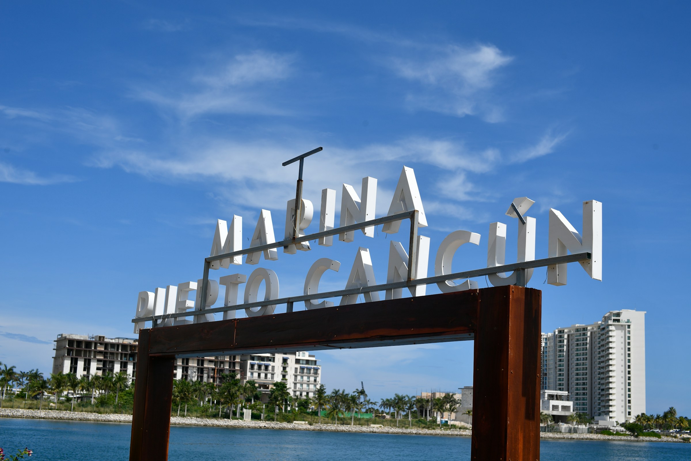 El letrero de la Marina Puerto Cancún sobre el canal, con las torres del desarrollo al fondo.